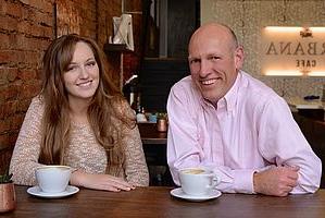 Karl and Lindsey sitting at a café; drinking coffee and smiling